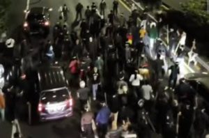 Rombongan orang yang mengenakan ikat kepala putih serta membawa bambu atau tongkat turun dari sejumlah kendaraan di kawasan Slipi. (Foto / Istimewa)